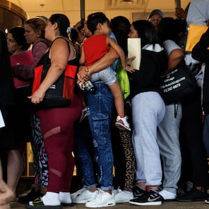 A group of migrants and members of the public wait in line outside an Illinois Department of Human Services office.