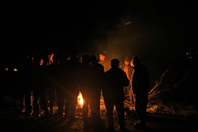 A photograph of refugees from Nagorno-Karabakh gather around a fire to warm themselves after getting stuck in a queue of vehicles on the road leading towards the Armenian border, in Nagorno-Karabakh, September 25, 2023.