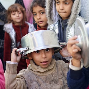 Palestinian children carry pots as they line up to receive food cooked by a charity kitchen in Rafah in southern Gaza.