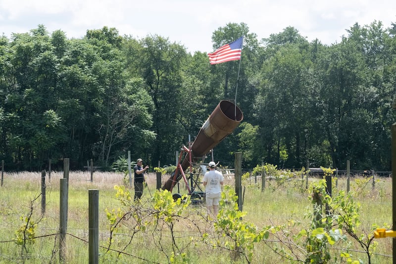 A still from episode two of How to With John Wilson of a rural setting with a telescope and an american flag.