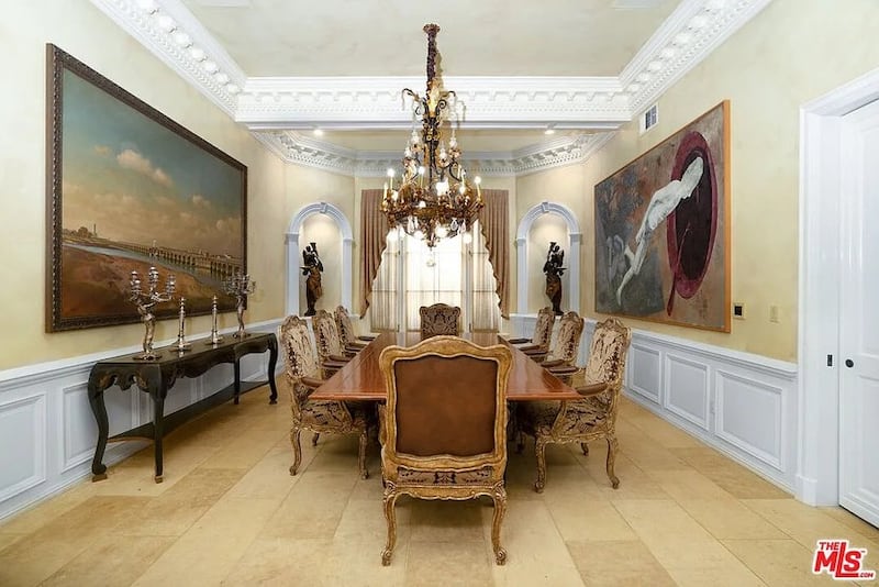 A formal dining room features a chandelier and large-scale oil paintings on the walls.