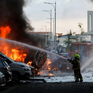 An emergency personnel works to extinguish the fire after rockets are launched from the Gaza Strip, as seen from the city of Ashkelon, Israel