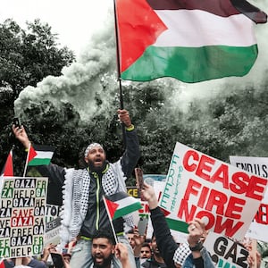 An illustration including a photo of a protester holding a flare and a Palestinian flag during a rally in support of Palestinians at the Texas State Capitol in Austin