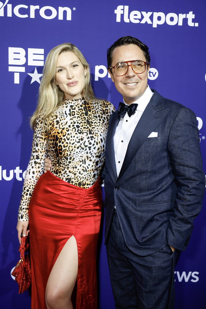 Ryan Lizza in a blue tuxedo and Olivia Nuzzi in leopard print top and red slit skirt