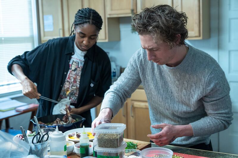 Ayo Ebebiri and Jeremy Allen White cook in a kitchen during a scene from The Bear Season 2.