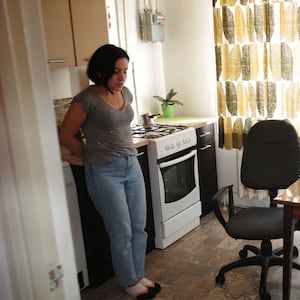 A photo shows a woman in her kitchen with the Ukranian flag in the foreground