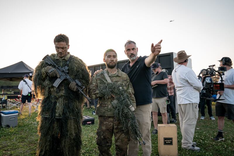 A behind the scenes picture of Alex Garland talking to actors on the set of Civil War