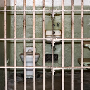 A picture of a jail cell, as seen through the bars.