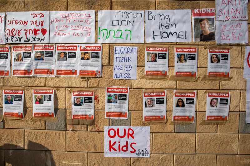 A protester walks past pictures of abductees at the entrance to the Israeli Ministry of Defense.