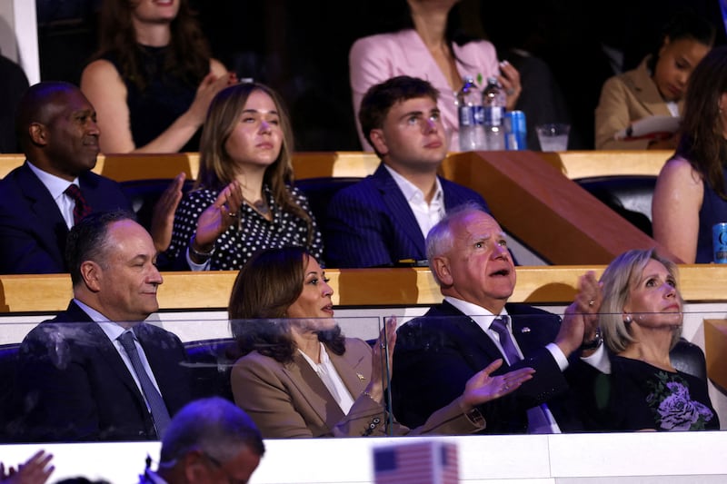 Tim Walz clapping at the DNC with his wife Gwen, Kamala Harris and Doug Emhoff and his children Hope and Gus behind him.