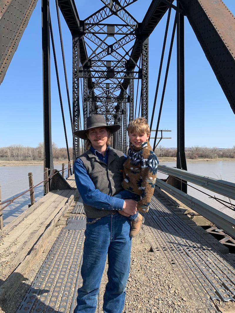 A picture of Isaac Carrier holding his son, Stetson, on a bridge