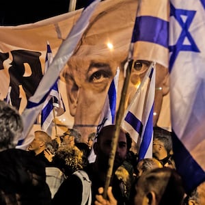 A photo of people waving Israeli flags with a picture of Benjamin Netanyahu poking out through the flags