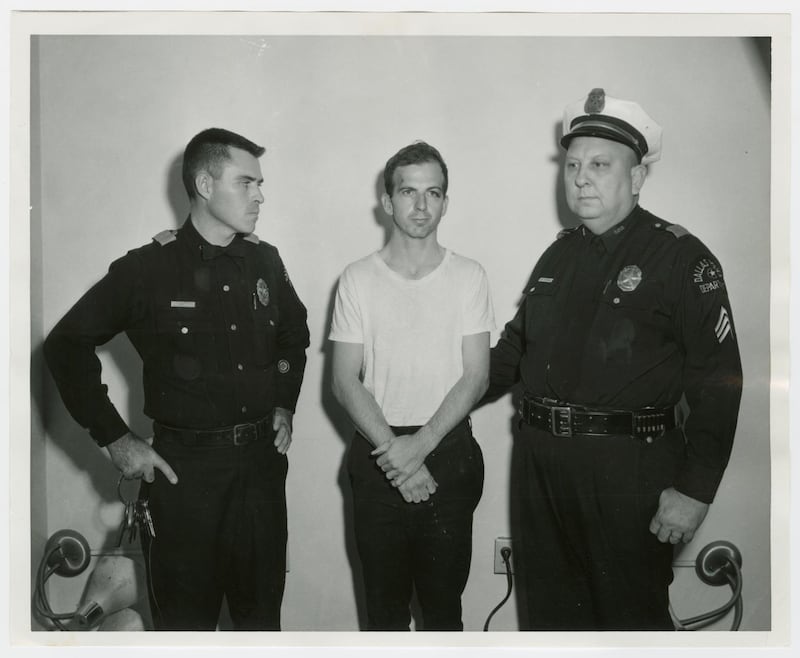 Lee Harvey Oswald handcuffed between two uniformed police