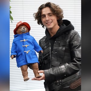 Photo of Timothée Chalamet posing with a statue of Paddington Bear.