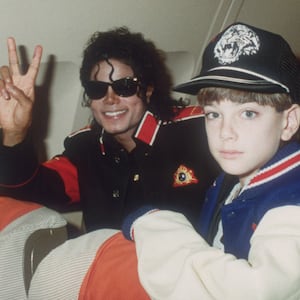 Michael Jackson throws a peace sign with Jimmy Safechuck on a tour plane