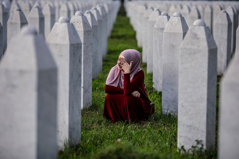 A Bosnian Muslim woman cries between graves of her father, two grandfathers and other close relatives, all victims of Srebrenica genocide.