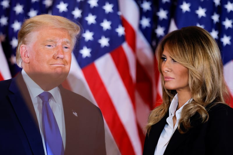 Donald and Melania Trump in front of a US flag