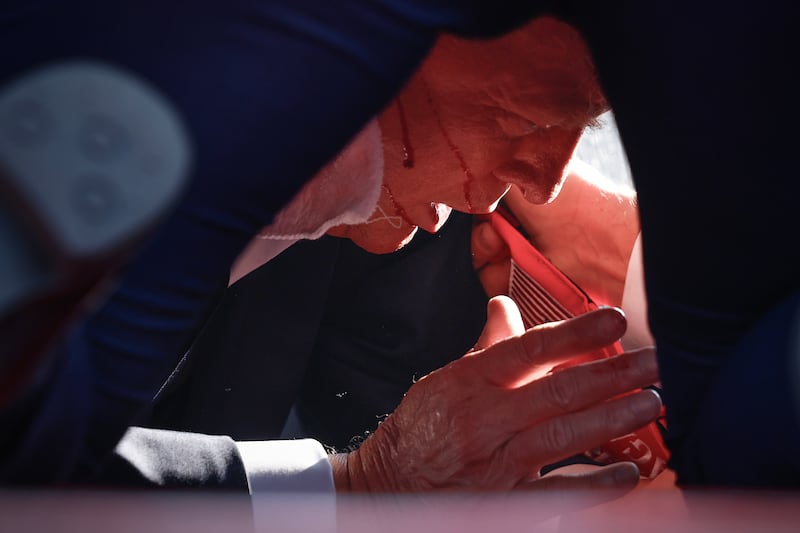 Trump with blood on his face seen through the shoes of Secret Service agents