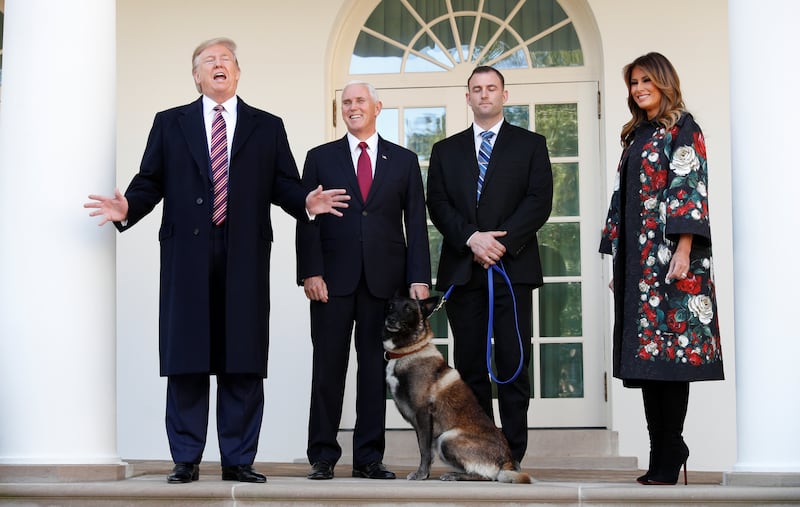 Then-President Donald Trump talks to the media as he poses with Vice President Mike Pence, first lady Melania Trump and Conan, the U.S. military dog that participated in the U.S. raid in Syria that killed ISIS leader Abu Bakr al-Baghdadi.