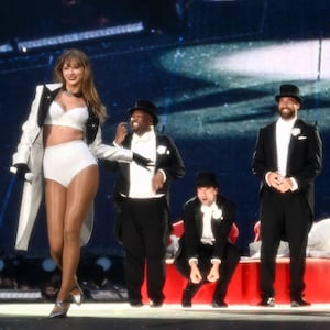 Taylor Swift poses on stage near a smiling Travis Kelce.