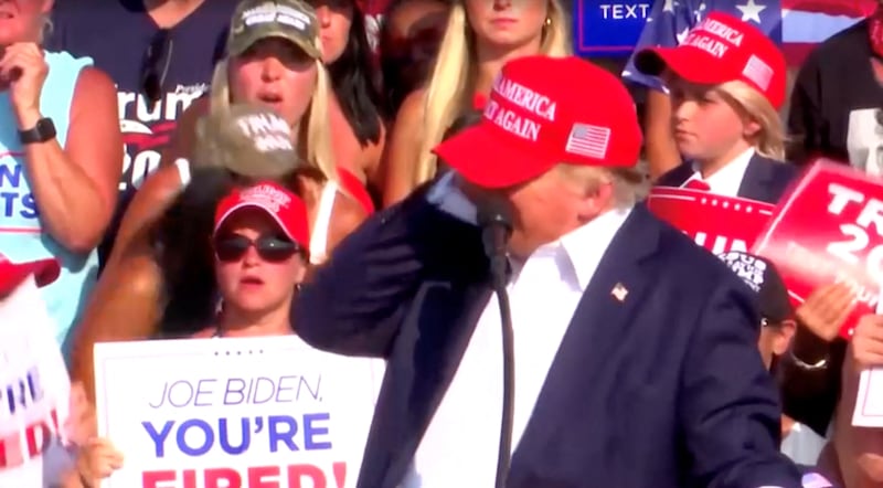 Donald Trump with his hand to his ear after a bullet grazed him