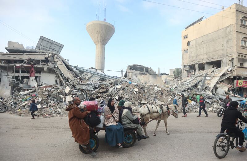 An image of Palestinians walking by rubble in Gaza.