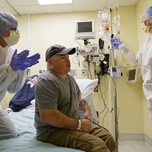 In this photo taken Monday, Nov. 13, 2017, Brian Madeux, 44, starts to receive the first human gene editing therapy for Hunter syndrome, as his girlfriend Marcie Humphrey, left, applauds at the UCSF Benioff Children's Hospital in Oakland, Cal.