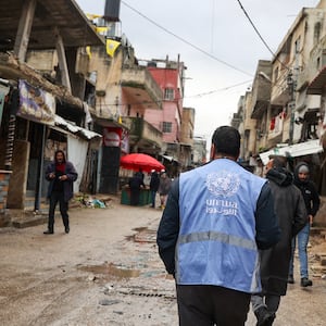 A man wearing a jacket bearing the logo of the United Nations Relief and Works Agency for Palestine Refugees