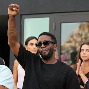 Diddy raising his fist with DJ Khaled behind him