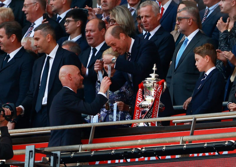 Manchester United manager Erik ten Hag collects his winners medal from Britain's Prince William, Prince of Wales as Prince George looks on.