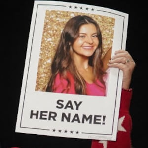 Supporters of Donald Trump hold up photos of Laken Riley and posters that say, “SAY HER NAME.”