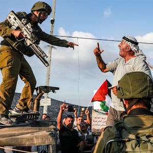 A photo of a Palestinian protester and an IDF soldier shouting at each other. 