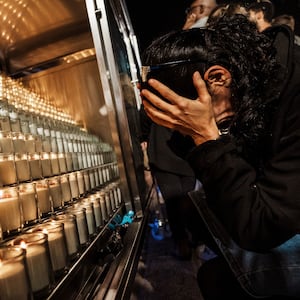 A picture of a woman weeps in her hands in front of rows of candles.