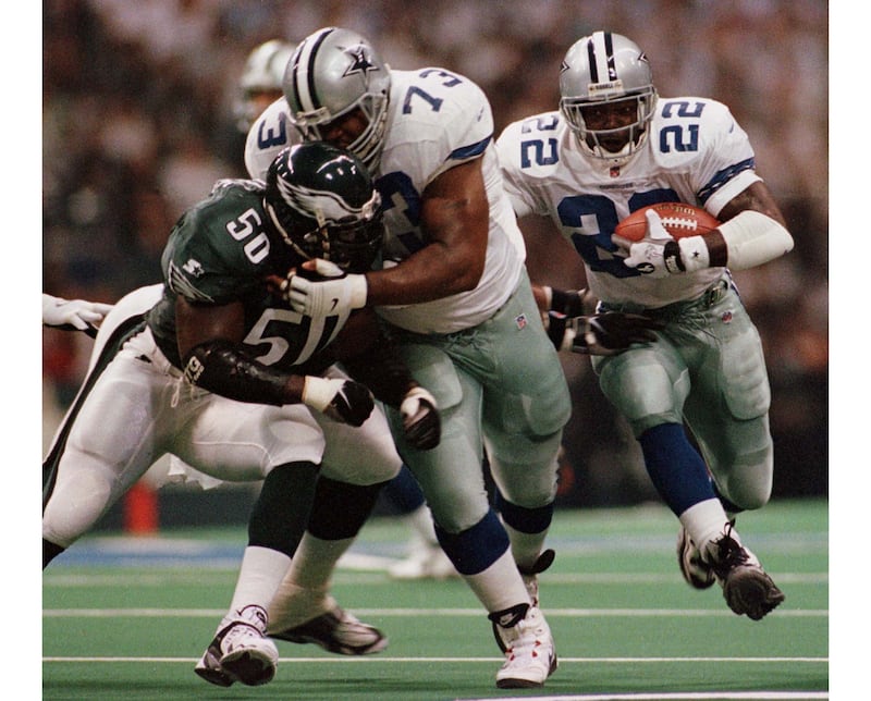 Emmitt Smith (#22) rushes for a five-yard gain as Larry Allen (#73) blocks the Philadelphia Eagles’ Darrin Smith (#56) during a game in 1997.