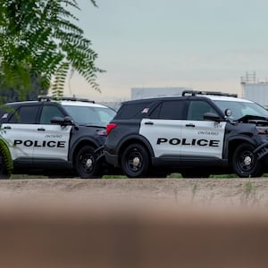  A police officer stands next to an Ontario police vehicle with front end damage