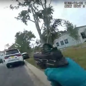 Screengrab from body-camera footage showing an officer with his gun drawn in the direction of his patrol vehicle.