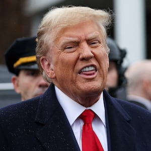 Donald Trump, wearing a suit and red tie, speaks in front of police officers.