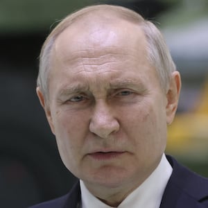 Russian President Vladimir Putin speaks during his meeting with workers at the Obukhov State Plant with a military vehicle in the background