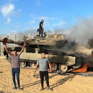 Palestinians cheer as an Israeli military vehicle burns after it was hit by Palestinian gunmen