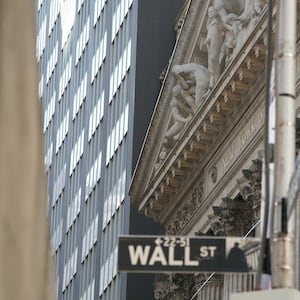 The exterior of the New York Stock Exchange (NYSE) in New York with a Wall St. sign in front of it.