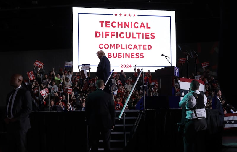 Donald Trump in front of a "technical difficulties" sign after his microphone stopped working during a campaign rally.