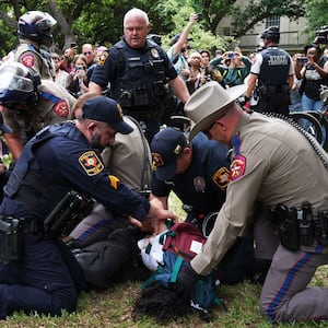 A photo including a student being detained by police on the campus of the University of Texas in Austin