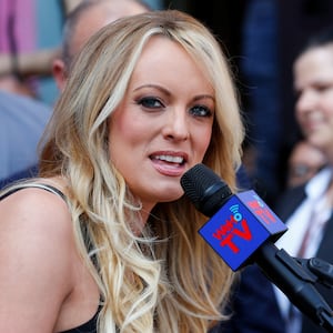 Stormy Daniels looks to her right while speaking into a handheld microphone.