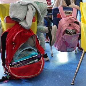 Student backpacks hang on the backs of classroom chairs in a New York City public school.