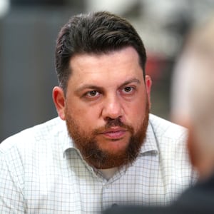 Leonid Volkov looks forward and listens in a conversation with someone facing him at a table.