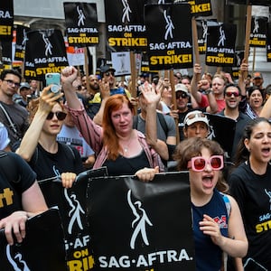 Members of the Writers Guild of America East and SAG-AFTRA cheer and react as they walk the picket line outside Netflix.