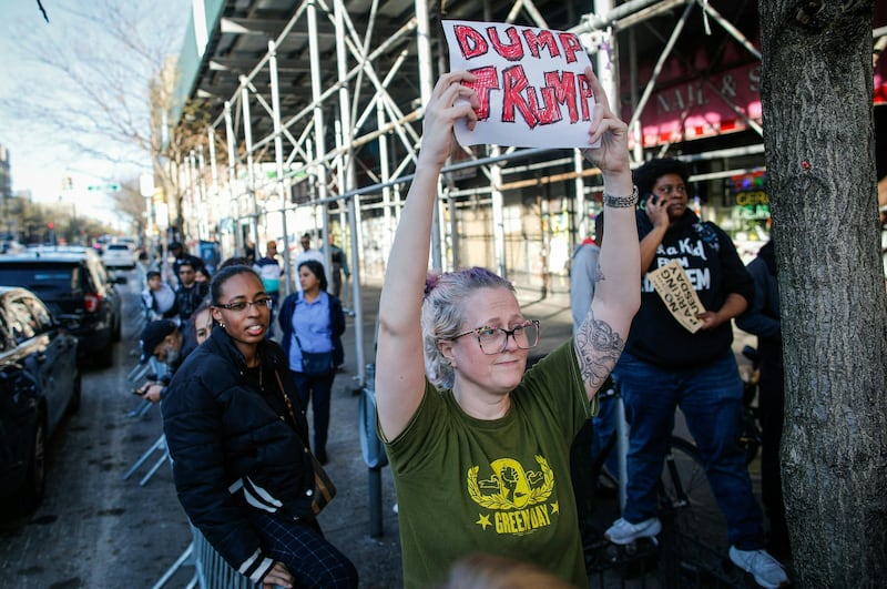 A New Yorker holds a placard ahead of Donald Trump’s arrival in Harlem.