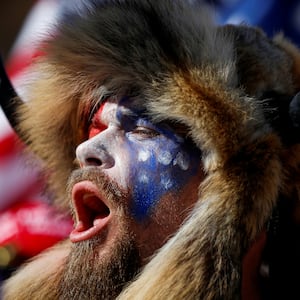 Jacob Chansley, wearing face paint and a fur hat, screams during a protest.