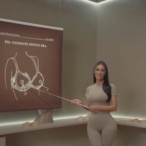 Kim Kardashian uses a pointer to direct attention to a diagram of her shapewear line's new Ultimate Nipple Bra.