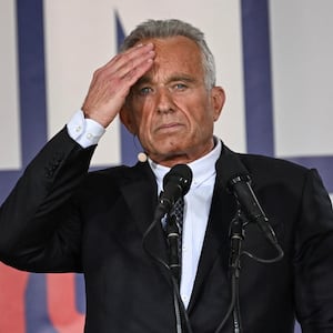 Robert F. Kennedy Jr. holding a hand to one temple at a campaign event.